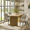 image of rectangular oak dining table with fluted rectangular pillar legs, surrounded by cream dining chairs