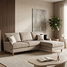 image of mink coloured velvet corner sofa with light wood legs, on soft rug in living room scene