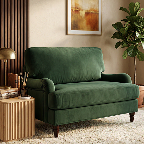image of forest green velvet snuggle chair with dark wood legs on soft carpet
