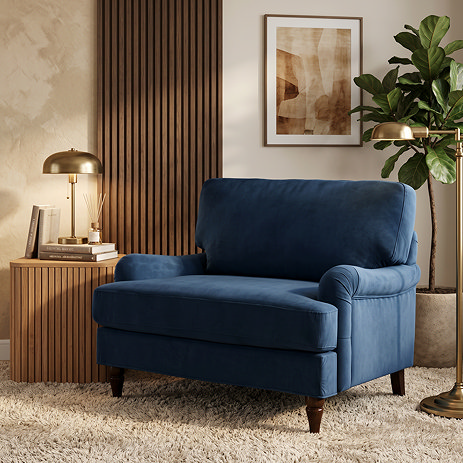 image of navy blue velvet snuggle chair with dark wood legs on cosy carpet