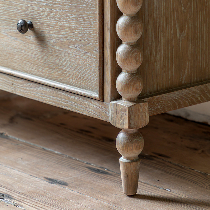 close up on hand-crafted bobbin detail of legs on limed oak chest of drawers