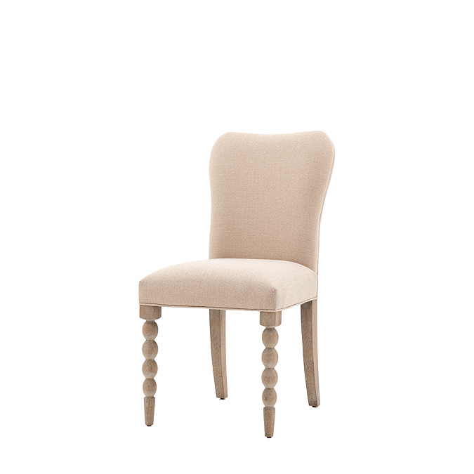 image cut out on white background of natural coloured upholstered dining chair with bobbin front leg detail