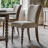 image of limed oak dining chair with bobbin front leg detail, tucked slightly under matching dining table