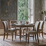 image of limed oak round extendable dining table with five chairs around it