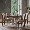 image of limed oak round extendable dining table with five chairs around it