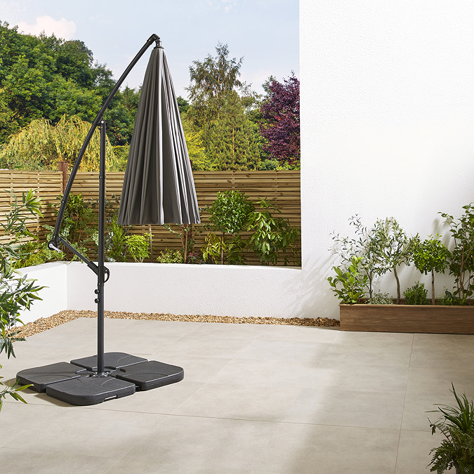 image of large grey parasol on empty sunny patio, closed and hanging down