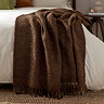 image of cocoa brown throw draped over the edge of a bed with cream duvet cover