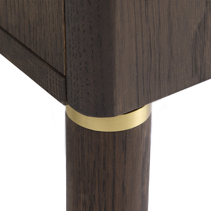 close up image of dark oak legs of tv lowboard, with gold band inlay detail where leg meets base of board