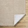 image of corner of soft beige rug folded over at corner to reveal material underneath
