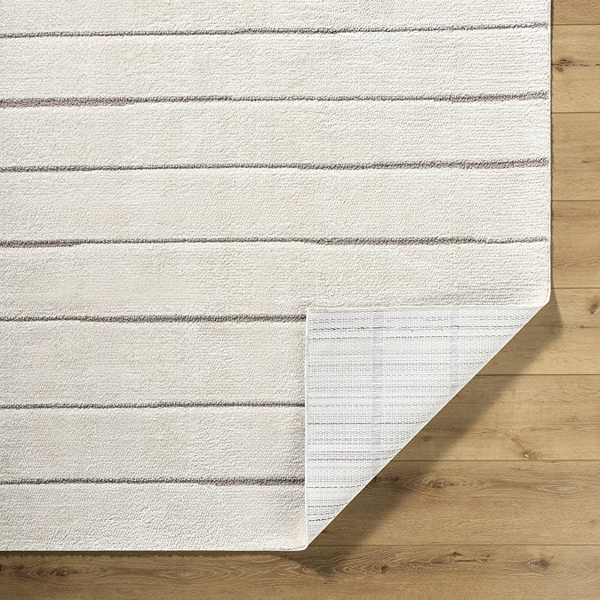 close up image on corner of ivory rug with lined pattern turned up slightly to reveal material underneath