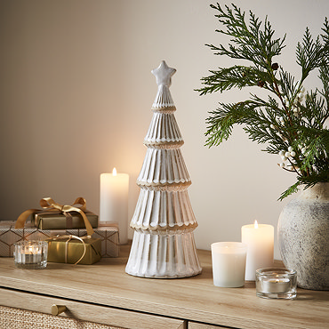 large ceramic tree next to medium ceramic tree on a sideboard, surrounded by cosy candles and a potted plant.