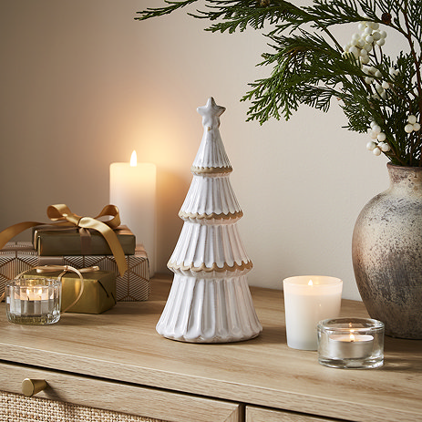 medium alora ceramic tree with star in a matte finish, displayed on a sideboard with cosy candles.