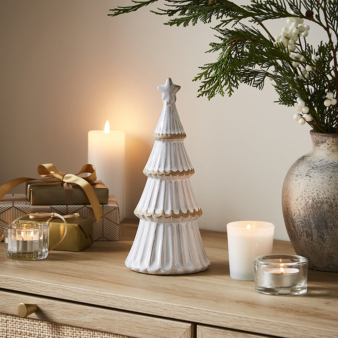 medium alora ceramic tree with star in a matte finish, displayed on a sideboard with cosy candles. 