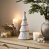 medium alora ceramic tree with star in a matte finish, displayed on a sideboard with cosy candles. 