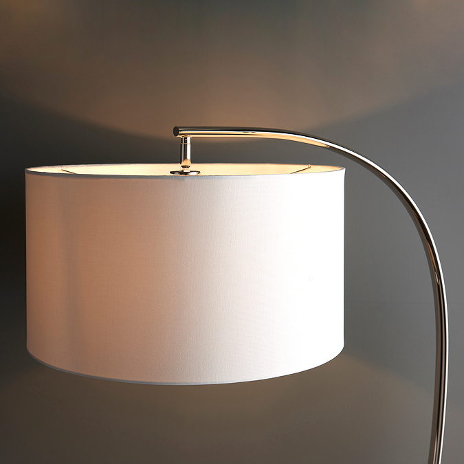 close up image of natural linen shade of curved nickel floor lamp, emitting soft warm glow