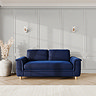 lifestyle image of large sofa with sculpted arms and light oak feet, in indigo velvet