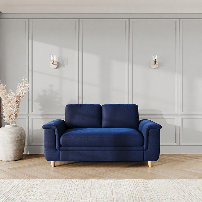 lifestyle image of medium sofa with sculpted arms and light oak feet, in indigo velvet