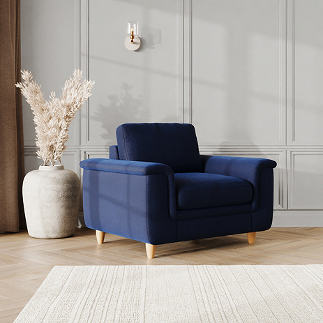 lifestyle image of snuggle chair with sculpted arms and light oak feet, in indigo velvet