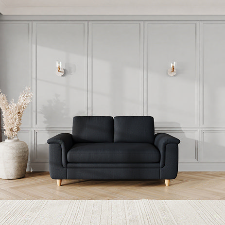 lifestyle image of medium sofa with sculpted arms and light oak feet, in midnight fabric