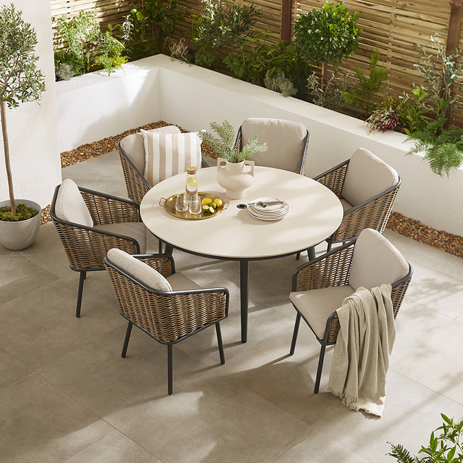 image taken from slightly above of round sintered stone dining table with wicker chairs and black legs