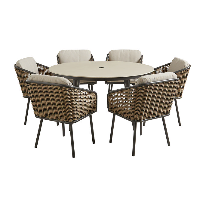 image cut out on white background of round stone sintered table with six wicker chairs with black legs