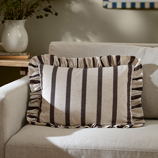 chocolate brown striped rectangle cushion placed on a cream sofa.