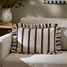 chocolate brown striped rectangle cushion placed on a cream sofa.