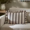 chocolate brown striped rectangle cushion placed on a cream sofa.