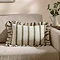 rectangular cushion with wide linen and narrow olive green stripes, sat on a cream sofa.