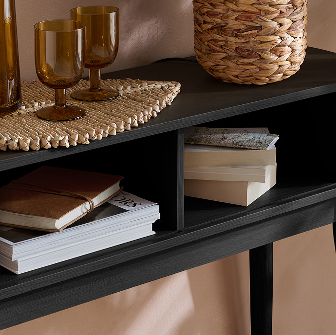 close up on inside of black console table with two storage sections, holding books