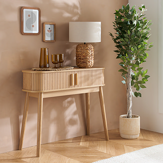 oak console table with two drawers and fluted sides, with slim legs and dressed with a lamp and glasses