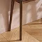 close up on dark brown slim left legs of console table