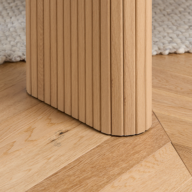 close up image of fluted legs of light oak dining bench, on wooden flooring