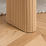 close up image of fluted legs of light oak dining bench, on wooden flooring