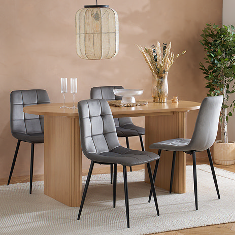 oval oak dining table with two stocky fluted legs and four grey chairs around it
