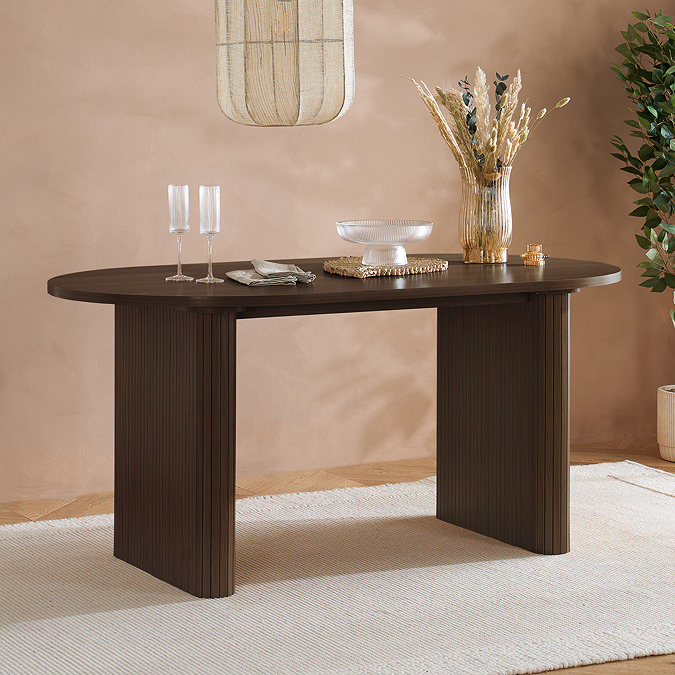 wide image of round dining table in dark walnut brown colour with homeware on top and boho mirror hanging above it