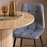 close up on smooth round edge of oak dining table and grey velvet chair in background