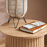 close up image of oak effect round side table with boho lamp and leather journal resting on top