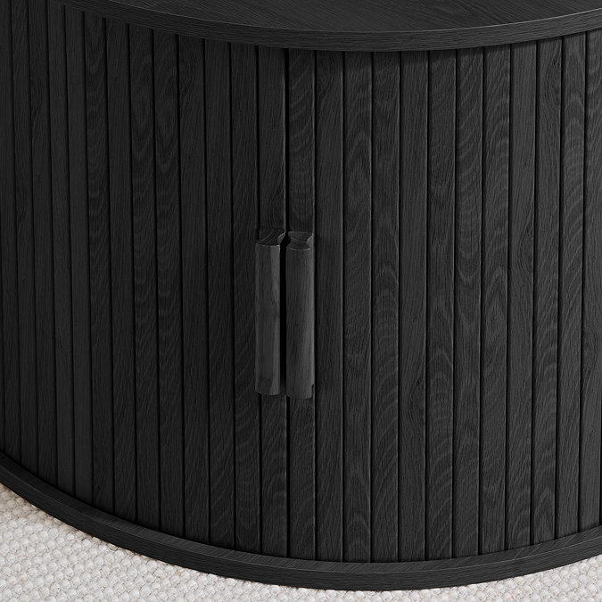 close up on black fluted doors of round storage coffee table, pulled shut