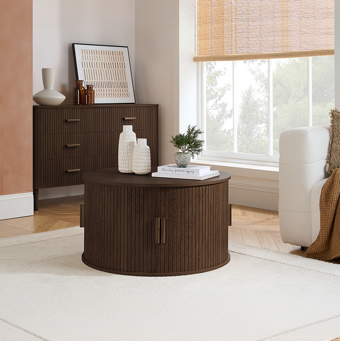 image of walnut brown fluted coffee table, round with doors, on cream rug