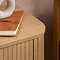 close up on corner of oak bedside table, smooth top and fluted body