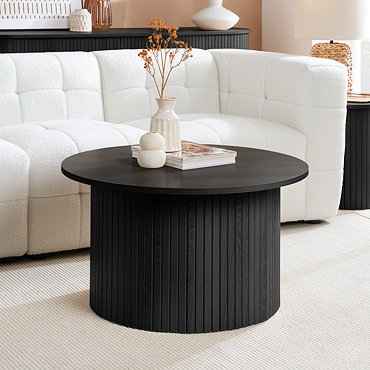 close up on smooth black top of wooden coffee table in front of white sofa, and topped with decorative vases