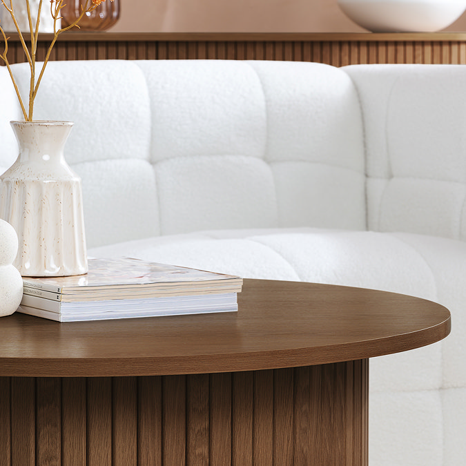 close up on walnut round coffee table with fluted detailing on the base and smooth finish 