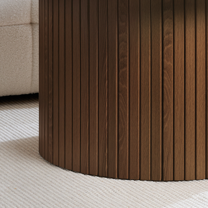 close up on fluted base of walnut coffee table on cream carpet