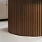 close up on fluted base of walnut coffee table on cream carpet