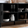close up image of black wooden sideboard with doors open, showing crockery and dishware on shelved within