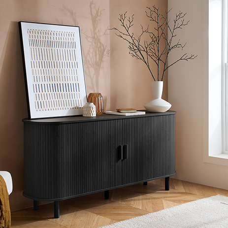 image of black fluted 2 door sideboard on wooden flooring of living room, topped with decorative accessories