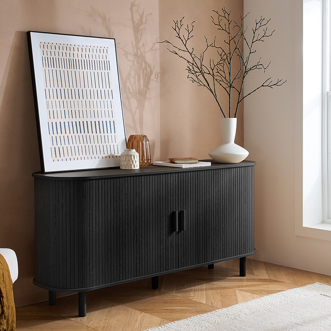 image of black fluted 2 door sideboard on wooden flooring of living room, topped with decorative accessories