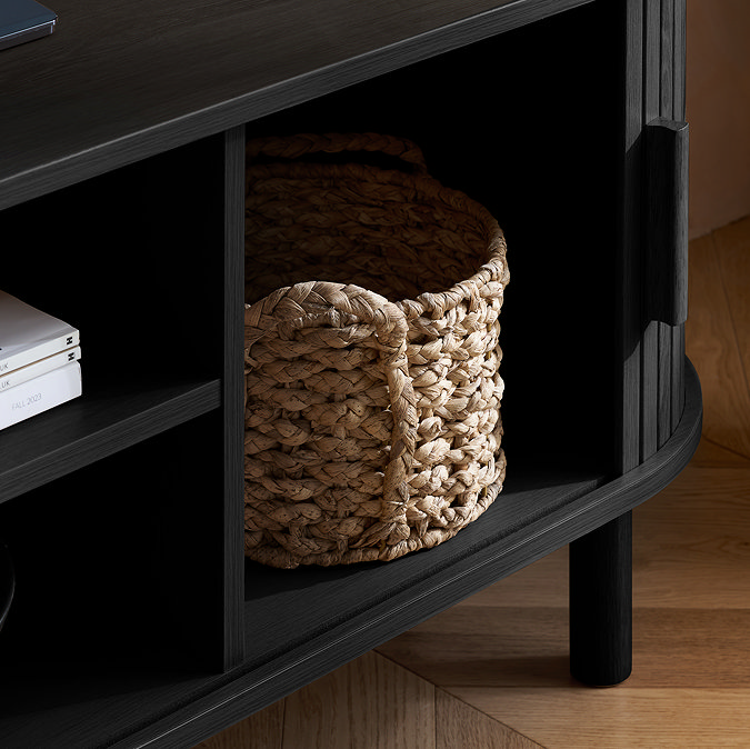 close up image of wicker basket in compartment space of black tv unit