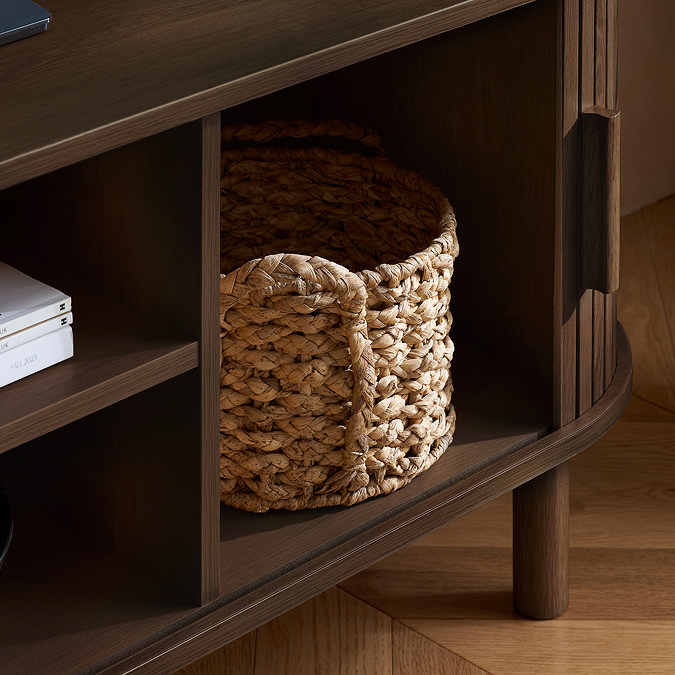 close up image of wicker storage basket in compartment of walnut wood tv unit